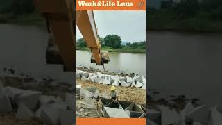 Excavator placing concrete tetrahedron shapes onto a river bank construction [upl. by Shiroma]