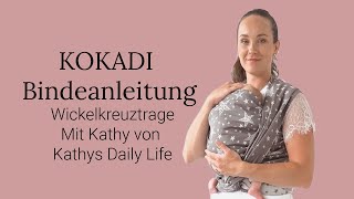 Babytrage Anleitung KOKADI Wickelkreuztrage vorne auf dem Bauch getragen Tragetuch Binden [upl. by Enyrhtac]